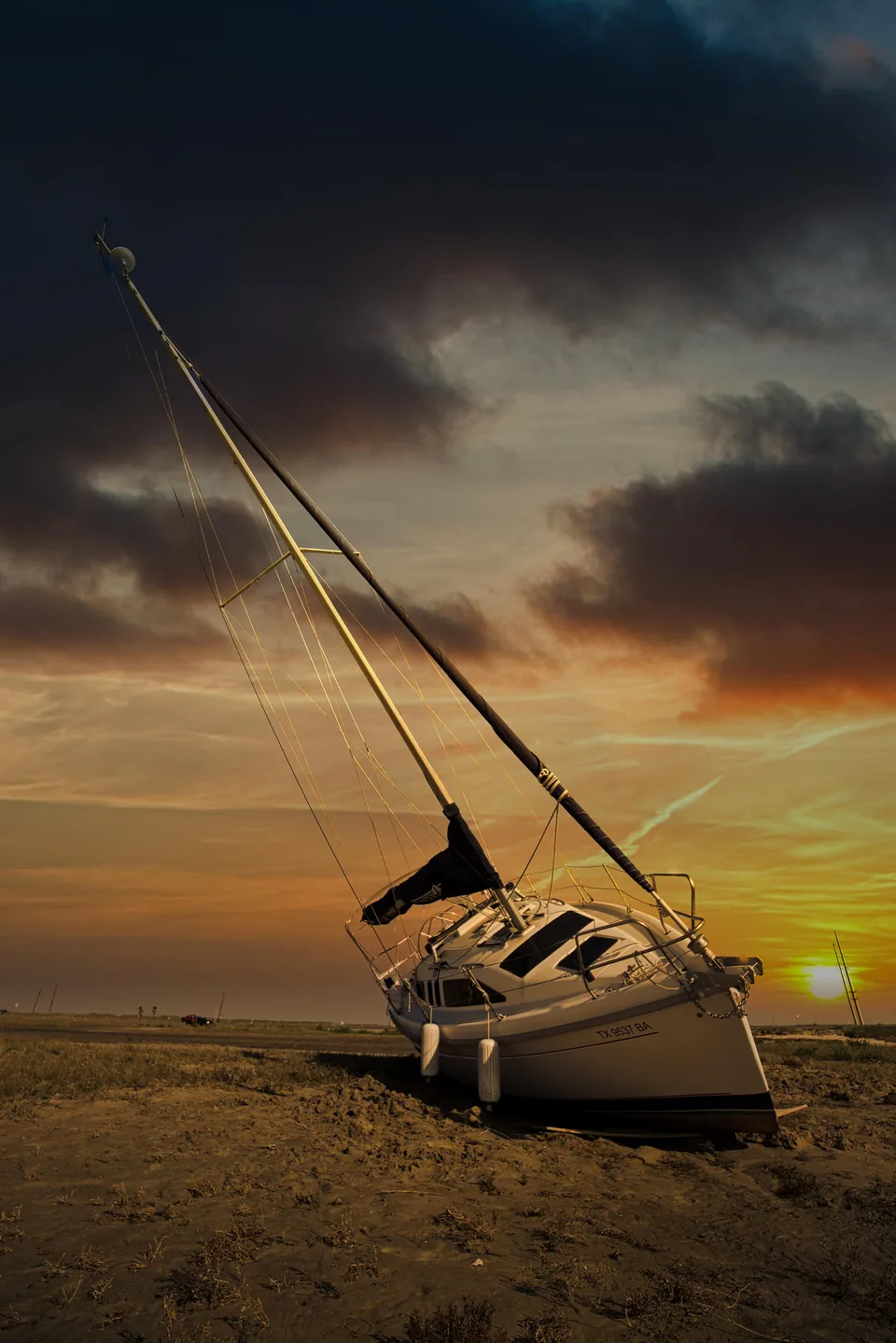 Sailboat beached on sand at sunset