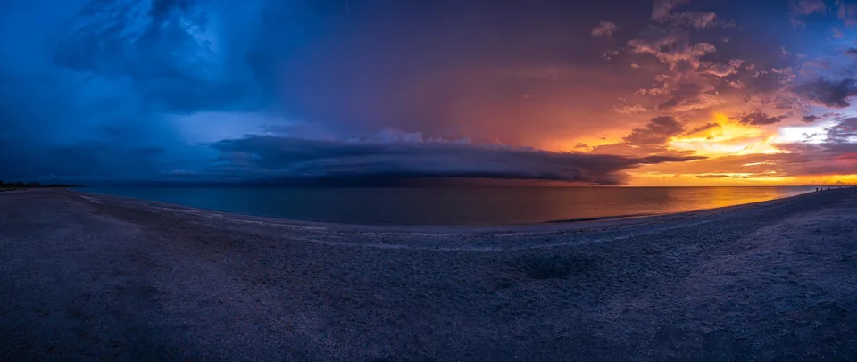 Panorama of a sunset storm over a calm shoreline
