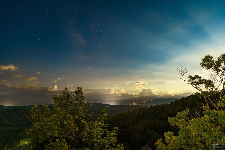Starry twilight over trees and a cloud-filled valley