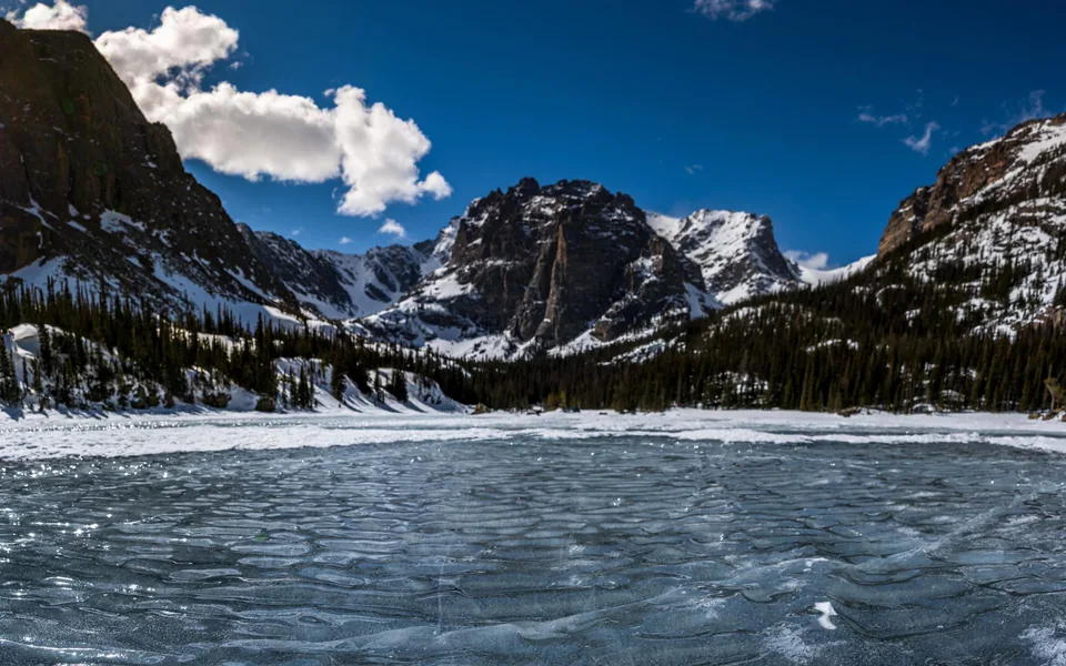 Frozen alpine lake ringed by rugged mountains