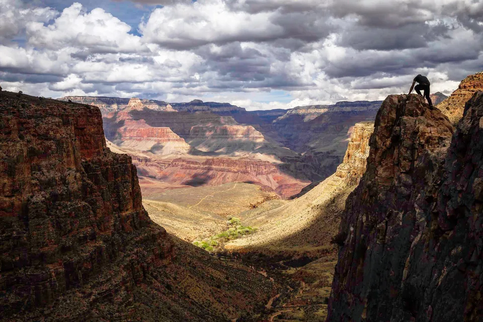 Hiker on a cliff edge overlooking the Grand Canyon