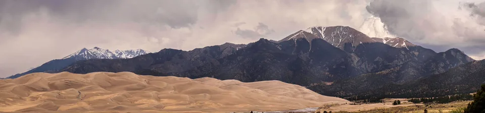 Panorama of sand dunes beneath mountains