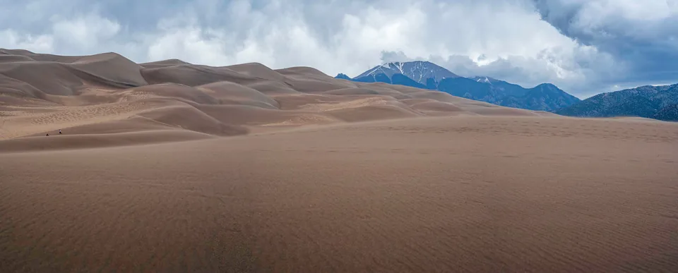 Sand dunes rolling toward distant mountains