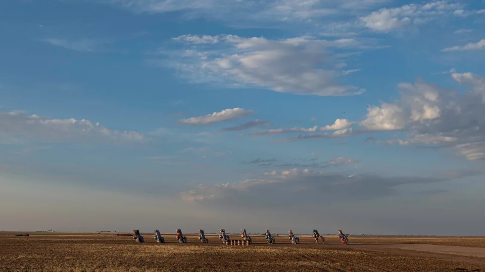 Distant herd crossing a vast plain beneath clouds