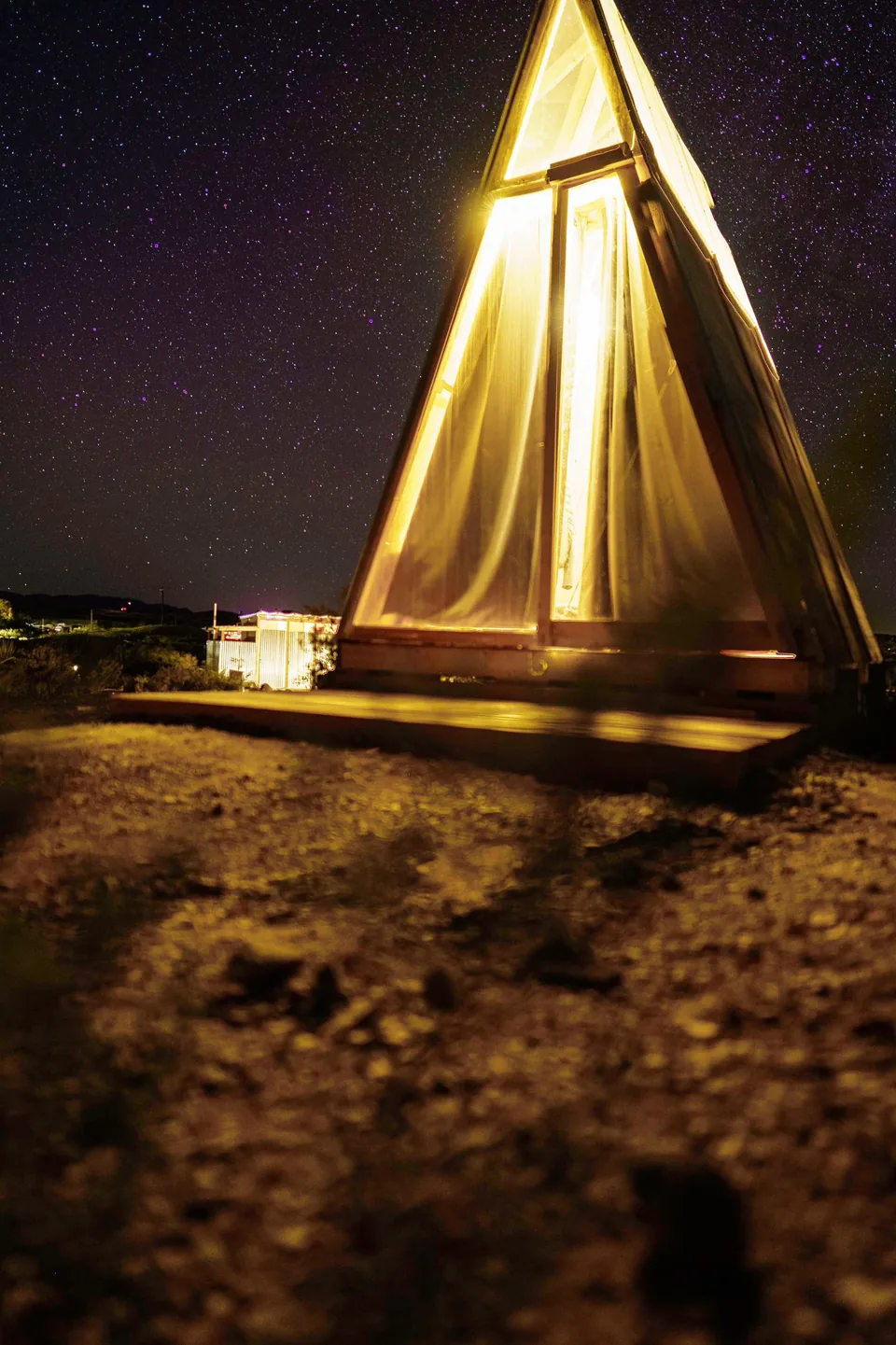 Lit A-frame tent beneath a night sky