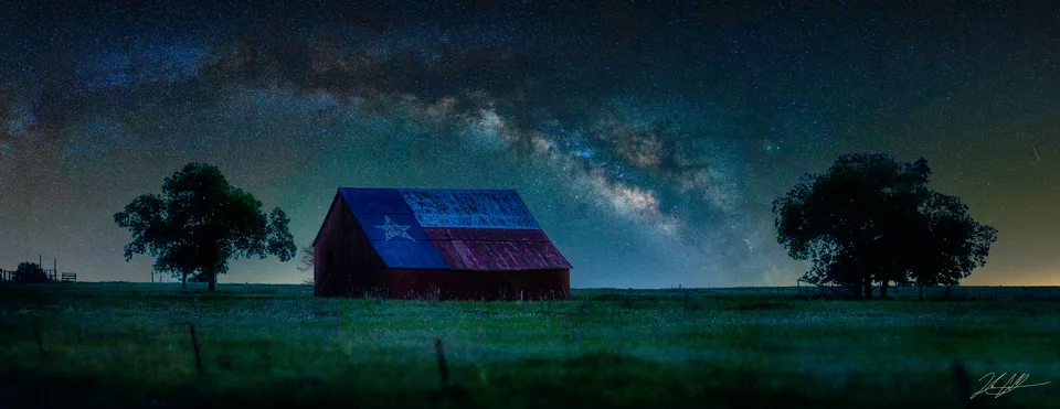 Panorama of a Texas-flag barn beneath the arching Milky Way