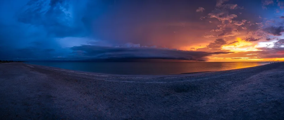 Panorama of storm clouds at sunset over a shoreline