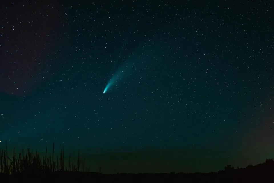 Comet streaking over a dark horizon